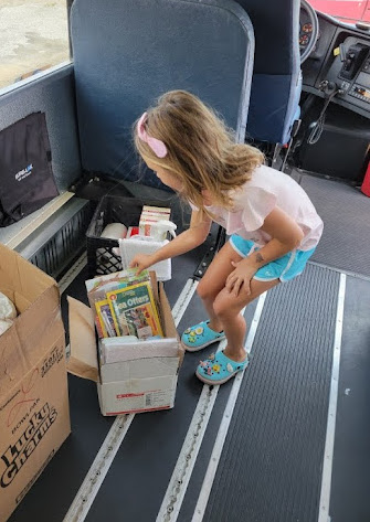 girl selecting a book from a summer book distribution