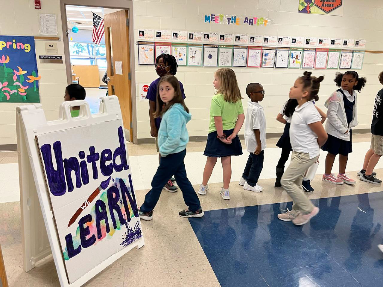 Students in the Hallway and the hand made United We Learn Sign