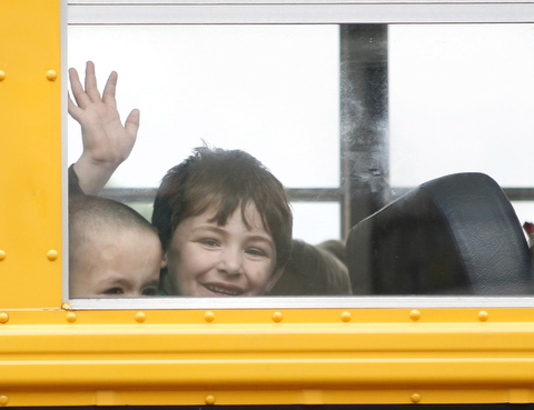 Photo of child waving from a school bus window.